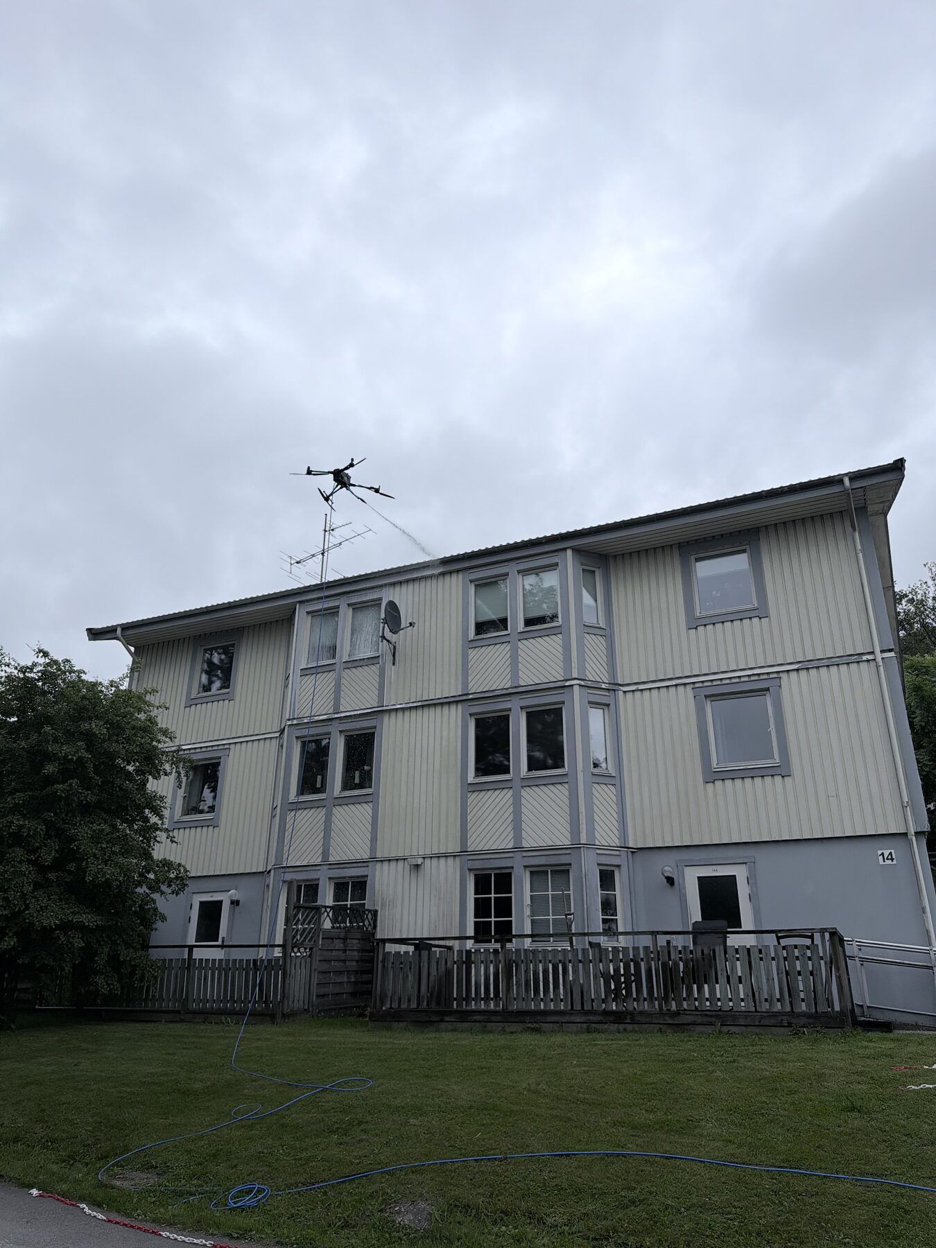 Drönare tvättar gul träfasad på trevåningshus i Göteborg
