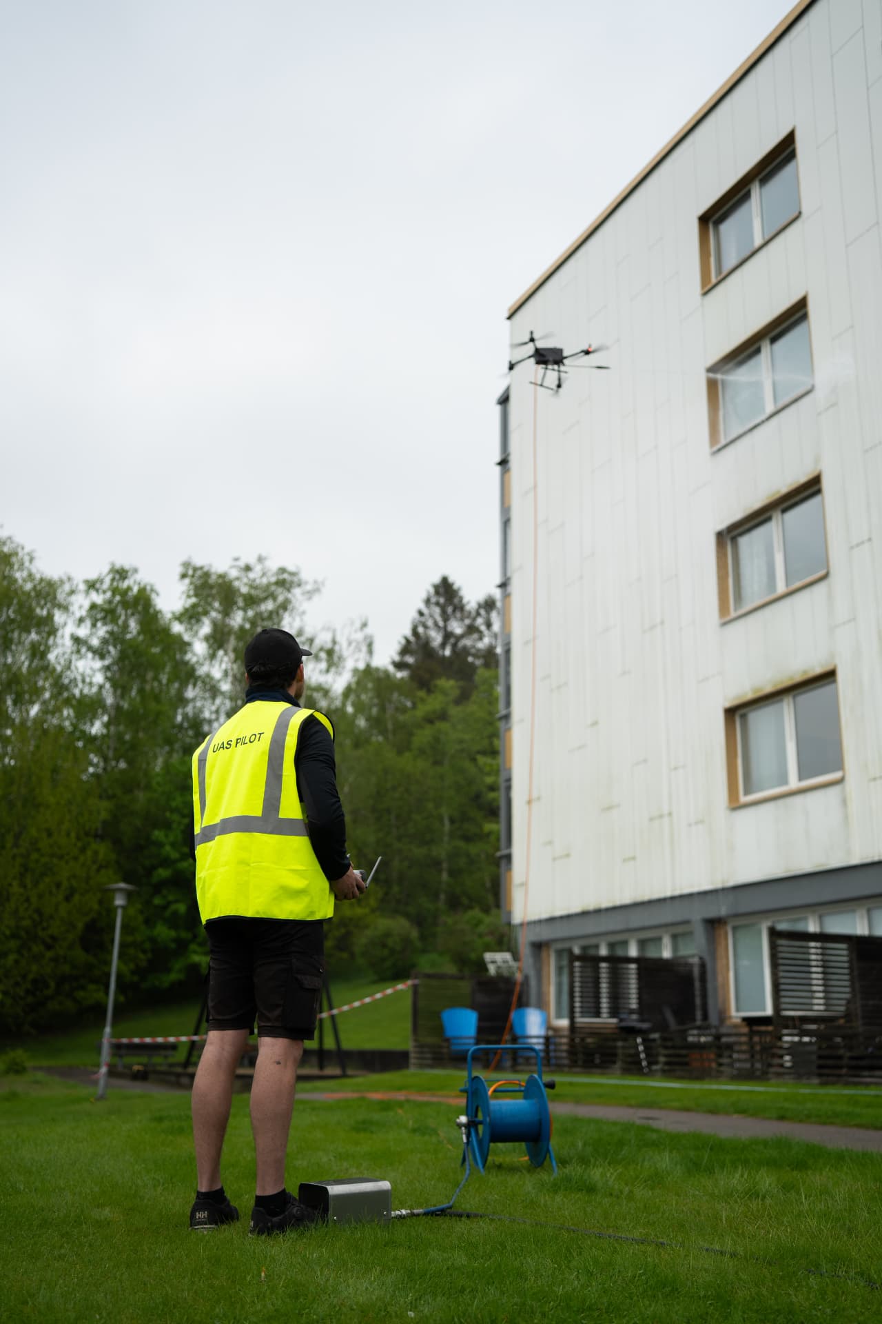 UAS-pilot styr drönaren från marken vid fasadtvätt av BRF-fastighet