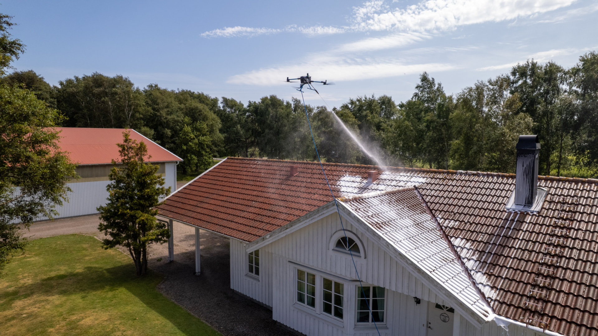 Drönare sprutar rengöringsmedel på tak och fasad från luften